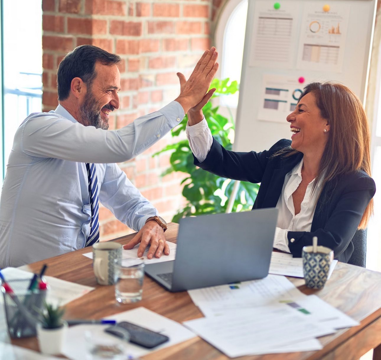 Zwei Professionals geben sich am Schreibtisch ein High Five